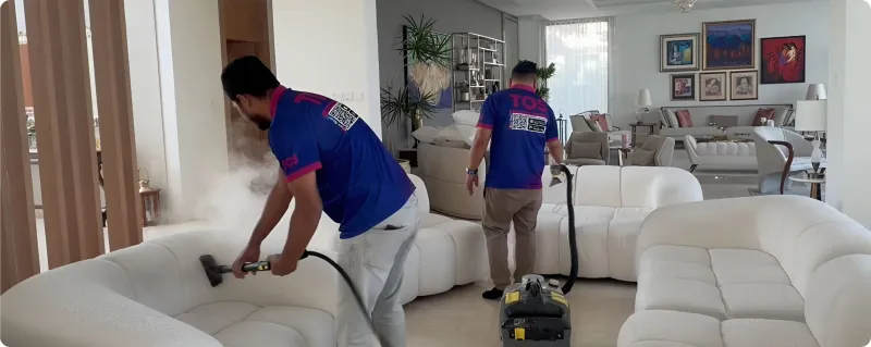 TopOne technician steam-cleaning a white fabric sofa